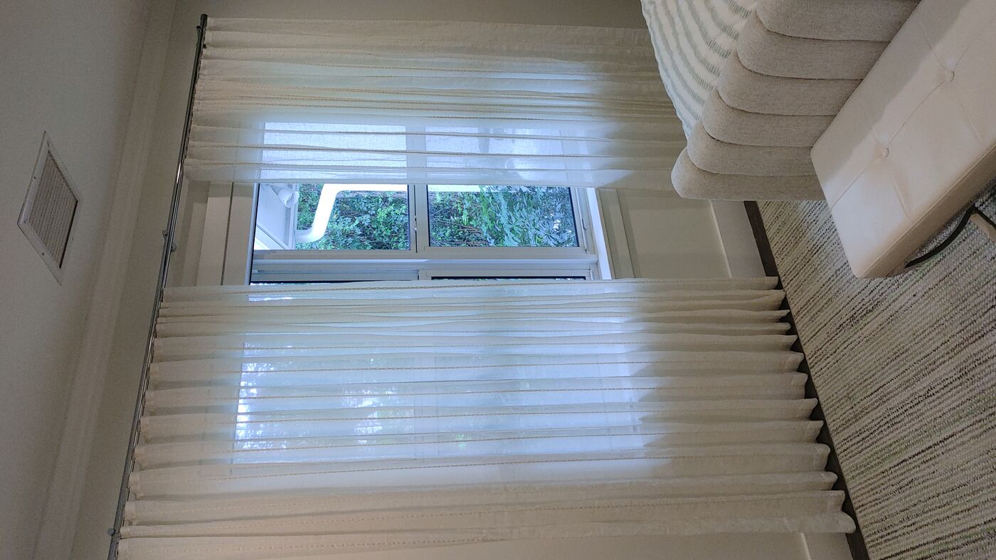 Sheer pinch-pleat curtains installed in a bedroom